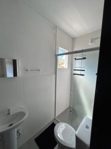 a white bathroom with a toilet and a sink at Pousada Tamatoa Suítes in Florianópolis