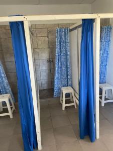 a shower with blue curtains and two stools in a bathroom at Alfar Hostel in Mar del Plata