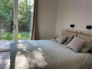 ein Bett in einem Schlafzimmer mit einem großen Fenster in der Unterkunft Chalet goudmeer LUXURY AIRCO WIFI 3 bedrooms 2 bathrooms in Oosterwolde