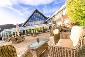 eine Terrasse mit Korbstühlen und Tischen sowie ein Gebäude in der Unterkunft Cedar Court Hotel Huddersfield in Huddersfield