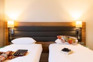 two beds in a room with white sheets and books at Moxy Glasgow Merchant City in Glasgow