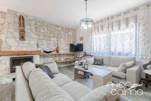 a living room with a couch and a stone wall at Villa Ra by MarCalma in Les tres Cales
