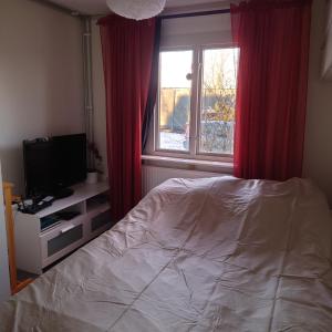 a bedroom with a bed and a window with red curtains at Lyckans Lodge in Dösjebro