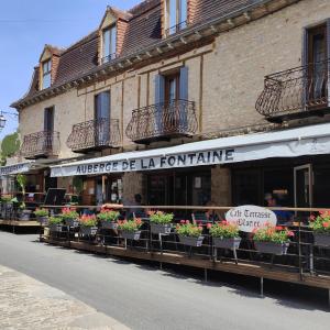 un bâtiment avec des plantes en pot dans une rue dans l'établissement Auberge de La Fontaine, à Autoire