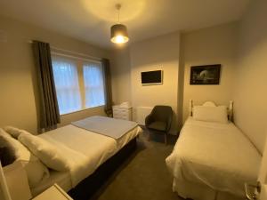 a bedroom with two beds and a chair and a window at Baldara House in Dublin