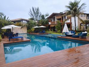 a pool at a resort with chairs and umbrellas at Apartamento Condomínio Villaggio di Mare - Barra Grande, Maraú - BA in Marau