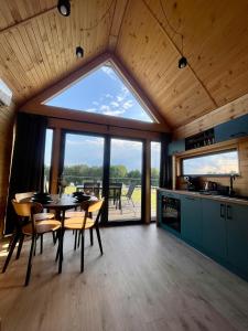 een eetkamer met een tafel en een groot raam bij Pasterzewo 20 - domki Mazury in Pasterzewo