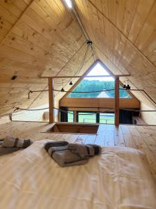 een bed in een houten kamer met een groot raam bij Pasterzewo 20 - domki Mazury in Pasterzewo