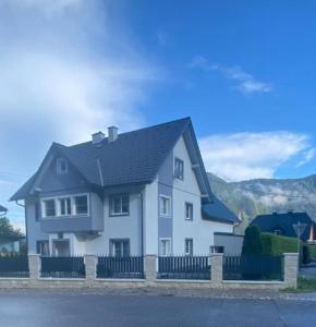 une maison blanche avec un toit noir derrière une clôture dans l'établissement Ferienwohnung Wolkenstein, à Wörschach