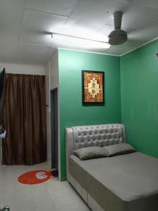 a bedroom with a bed with a green wall at RizqFateh Homestay in Kluang