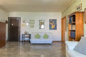 een woonkamer met een witte bank en een boekenplank bij Shell Apartment - Spazioso Attico Con WiFi Gratuito e Posto Auto in Perugia