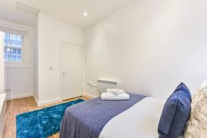 a bedroom with a large bed with blue rugs at 2 Bed Piccadilly Apartment- 1 in London