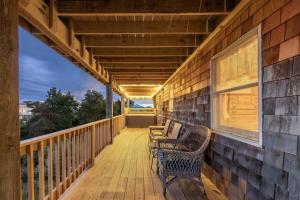 un portico con panchine sul lato di una casa di Seaside Serenity Awaits! Luxe Beach Retreat with Hot Tub a Salvo