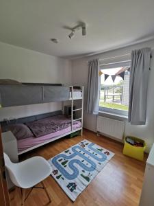 een slaapkamer met een stapelbed, een stoel en een tapijt bij Ferienhaus Lille Strandhus in Holnishof