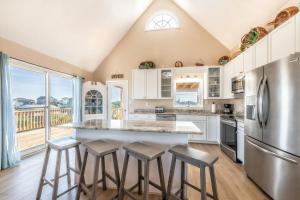 una cucina con armadi bianchi e una grande isola con sgabelli di Seaside Serenity Awaits! Luxe Beach Retreat with Hot Tub a Salvo