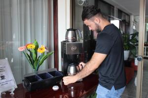 Ein Mann steht neben einer Kaffeemaschine in der Unterkunft Hotel América Heredia in Heredia