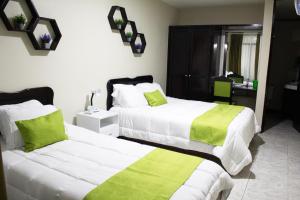 1 dormitorio con 2 camas con sábanas verdes y blancas en Hotel América Heredia en Heredia