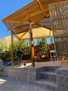 a wooden pavilion with a grill and chairs under it at Refugio Renacer in Pisco Elqui