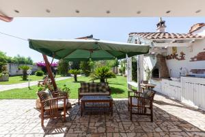 a patio with a table and chairs and a green umbrella at Villa Erika with private pool and garden - Happy Rentals in Lecce