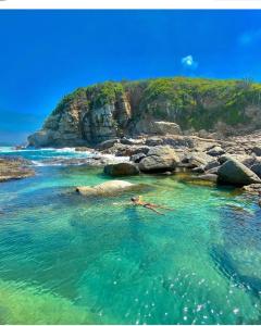 a person swimming in the water near a rocky beach at Casinha do Peró in Cabo Frio