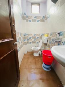 ein Badezimmer mit einem WC, einem Waschbecken und einem roten Eimer in der Unterkunft Hari Ganga Near By Bus And Railway Station in Haridwar