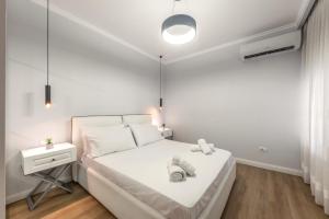 a white bedroom with a bed and a night stand at Luxurios Modern Apartment Marina Bay in Durrës