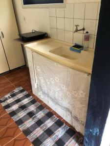 a kitchen counter with a sink and a rug at Casinha do Peró in Cabo Frio