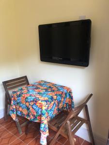 a table with a blanket on it with a tv on the wall at Casinha do Peró in Cabo Frio