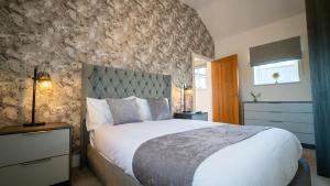 ein Schlafzimmer mit einem großen Bett und einer Steinwand in der Unterkunft Northumberland Luxury Stays - The Shearling in West Chevington