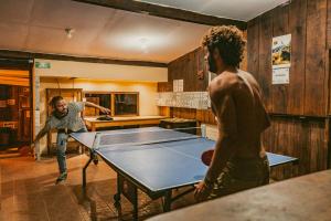 dos hombres jugando ping pong en una sala con una mesa de ping pong en Hostel Casa De Yagil, en San Cristóbal de Las Casas