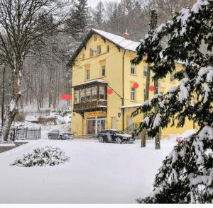 a yellow building in the snow with cars parked in front at Apartament GRACJA w Jedlinie Zdrój in Jedlina-Zdrój