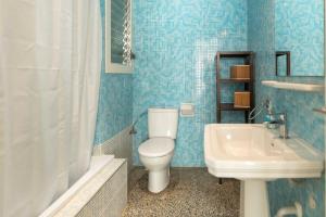 een blauw betegelde badkamer met een toilet en een wastafel bij Suitur apartamento frente a la playa de calafell in Calafell