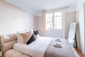 a white bedroom with a large bed and a window at Agréable appartement près de la capitale in Neuilly-sur-Seine