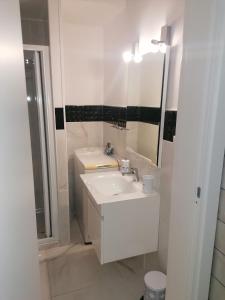 uma casa de banho branca com um lavatório e um espelho em Fiumicino Aeroporto Casa Vacanze Orchidea em Fiumicino