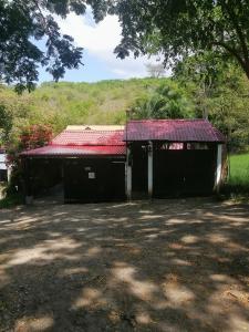 a small black building with a red roof at Casa campestre Rancho San Juan in El Pantano