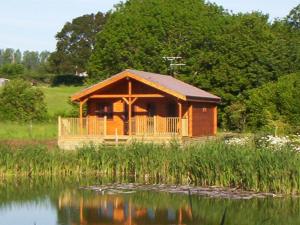 eine Blockhütte an einem See mit Reflexion im Wasser in der Unterkunft Watermeadow Lakes & Lodges in North Perrott