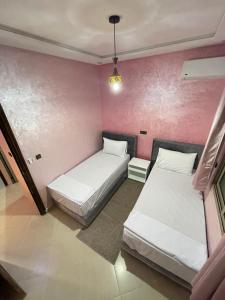 two beds in a room with pink walls at holiday homes ideal for families at IGHIZINN resort in Er Rachidia