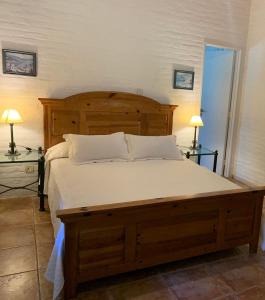 um quarto com uma grande cama de madeira e 2 candeeiros em LA QUINTA em Capilla del Señor