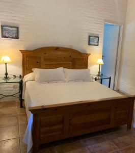 a bedroom with a large wooden bed with two lamps at LA QUINTA in Capilla del Señor