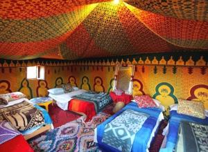 a room with four beds and a colorful ceiling at Desert Berber Fire Camp in Merzouga