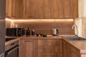 a kitchen with wooden cabinets and a sink and a microwave at Samos Tropic Apartments in Ríva