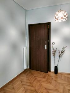 a wooden door in a room with a vase on the floor at Νέο ανακαινισμένο διαμέρισμα 70τμ στο Μαρούσι in Athens