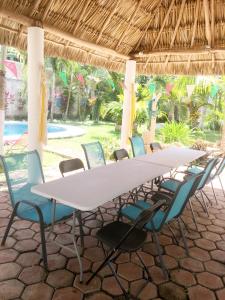 une longue table et des chaises blanches sous un parasol de paille dans l'établissement GREEN PARADISE LEONA VICARIO, à Leona Vicario