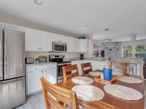 a kitchen with a wooden table with chairs and a refrigerator at Peaceful Beach Vacation, Heated Pool Access, Walk to Restaurants & More! in Tybee Island
