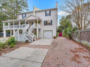a white house with a porch and a driveway at Peaceful Beach Vacation, Heated Pool Access, Walk to Restaurants & More! in Tybee Island