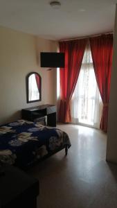 Hotel Ecologico Riverside في Quevedo: غرفة نوم بسرير ونافذة ذات ستائر حمراء