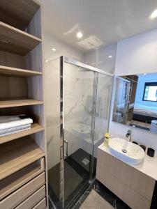 La salle de bains est pourvue d'une douche en verre et d'un lavabo. dans l'établissement T2 NEUF - Terrasse, à Rosny-sous-Bois