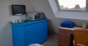 Habitación con armario azul y microondas. en Le chant des oiseaux, en Montmartin-sur-Mer