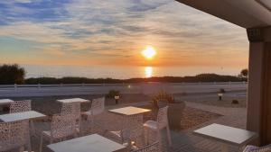 einen Sonnenuntergang über dem Meer mit Tischen und Stühlen in der Unterkunft La Vigie Vacances in Les Sables-dʼOlonne