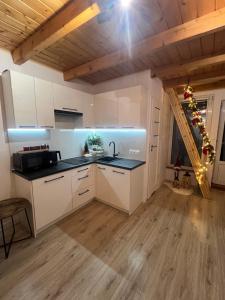 a kitchen with white cabinets and a wooden ceiling at Domek nad Popradem in Muszyna